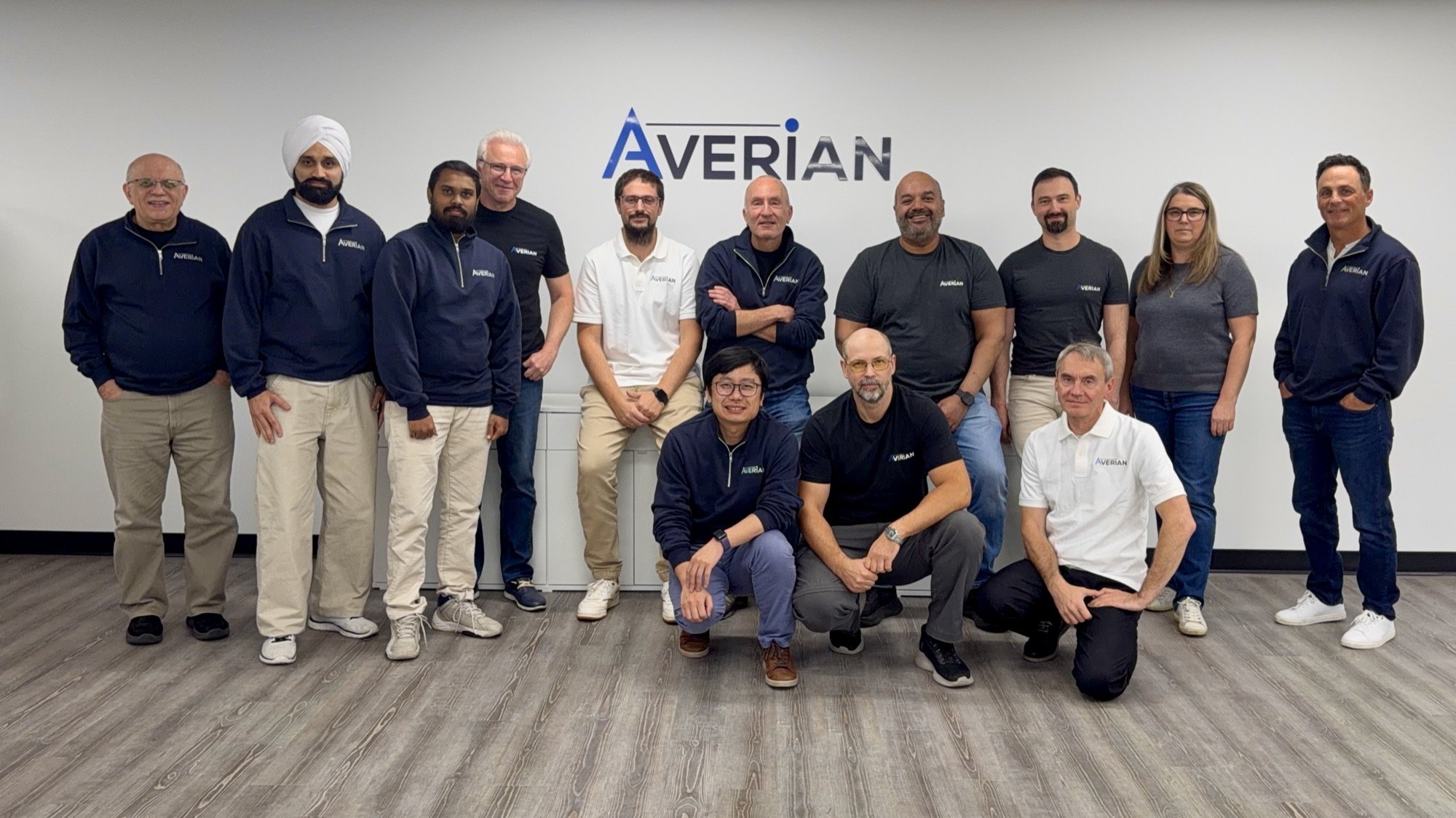 The Averian Ottawa team standing in front of the Averian logo in the new office